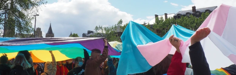 Photo : Josépha Vacquer photo d'un cortège de personnes portant un drapeau trans et un drapeau arc-en-ciel géants